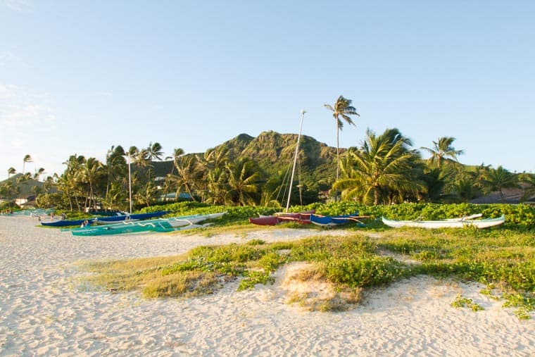 Canoes line Lanikai Beach, the Pillbox trail takes you to the top of the mountain in the distance.